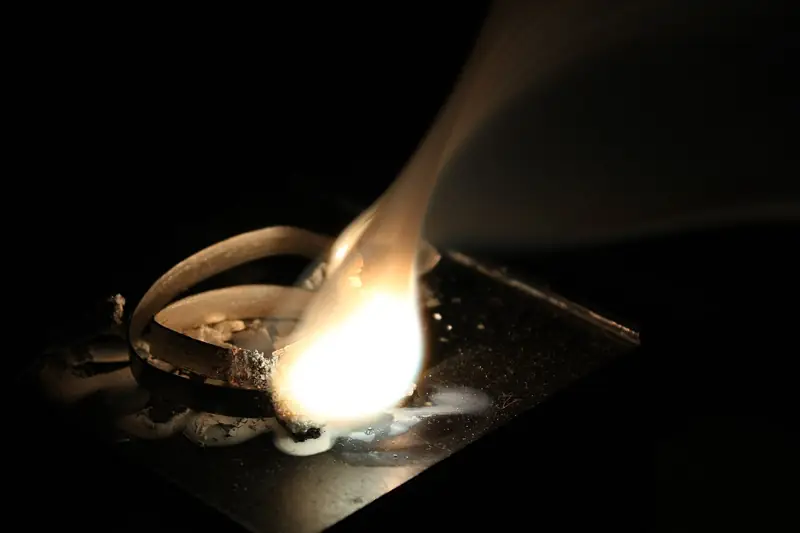 A magnesium ribbon held in tongs burning with a dazzling white flame